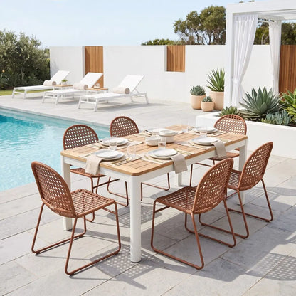 Outdoor dining set with a rectangular wooden table and six woven rattan chairs in a modern patio setting next to a swimming pool.