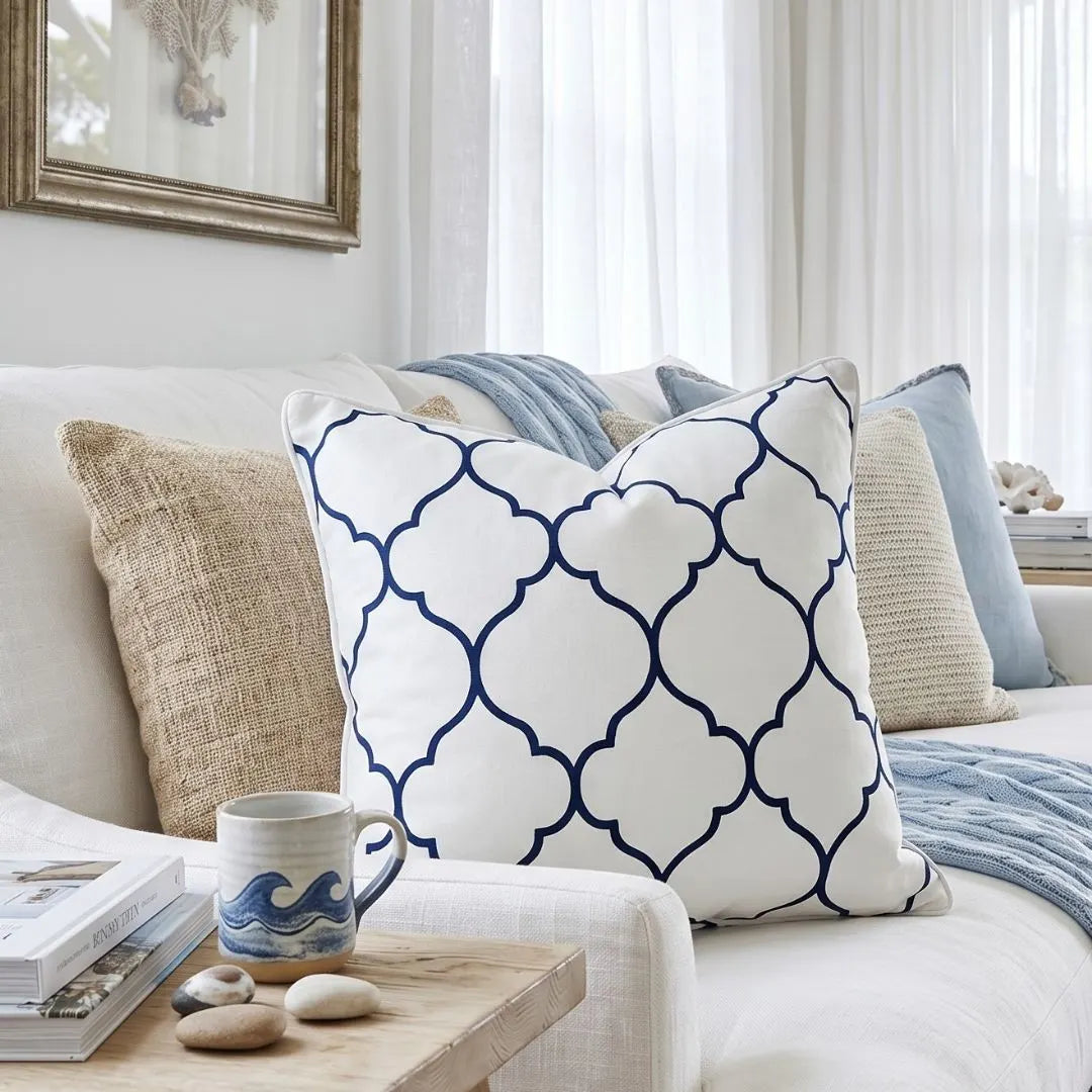 Decorative pillows on a sofa with a coffee mug and stones on a side table.