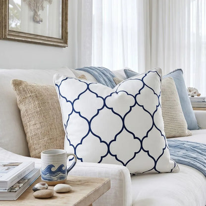 Decorative pillows on a sofa with a coffee mug and stones on a side table.