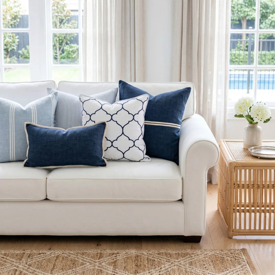 White sofa with blue and patterned cushions in a bright living room.