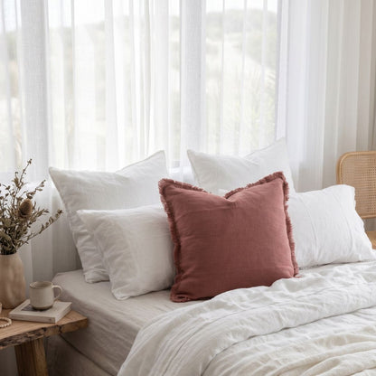 Hand loomed pink peony coloured cushion in a light and bright bedroom