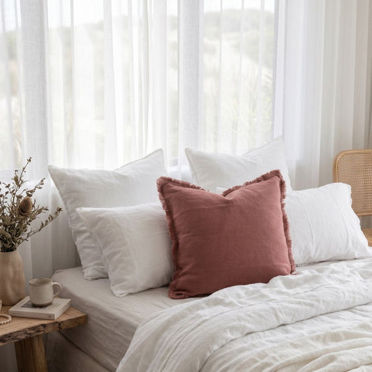 Hand loomed pink peony coloured cushion in a light and bright bedroom