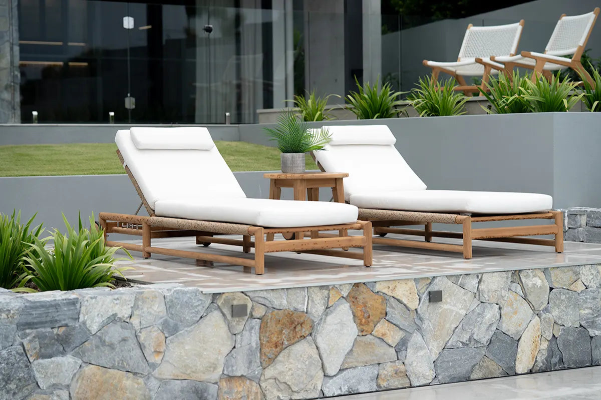 Two white lounge chairs with wooden frames on a stone patio area.
