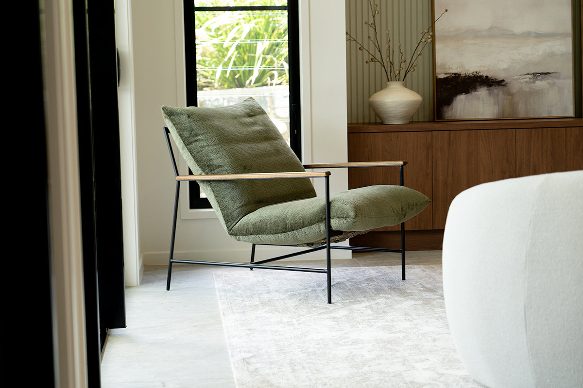 Green armchair in a modern living room with a white sofa and abstract painting.
