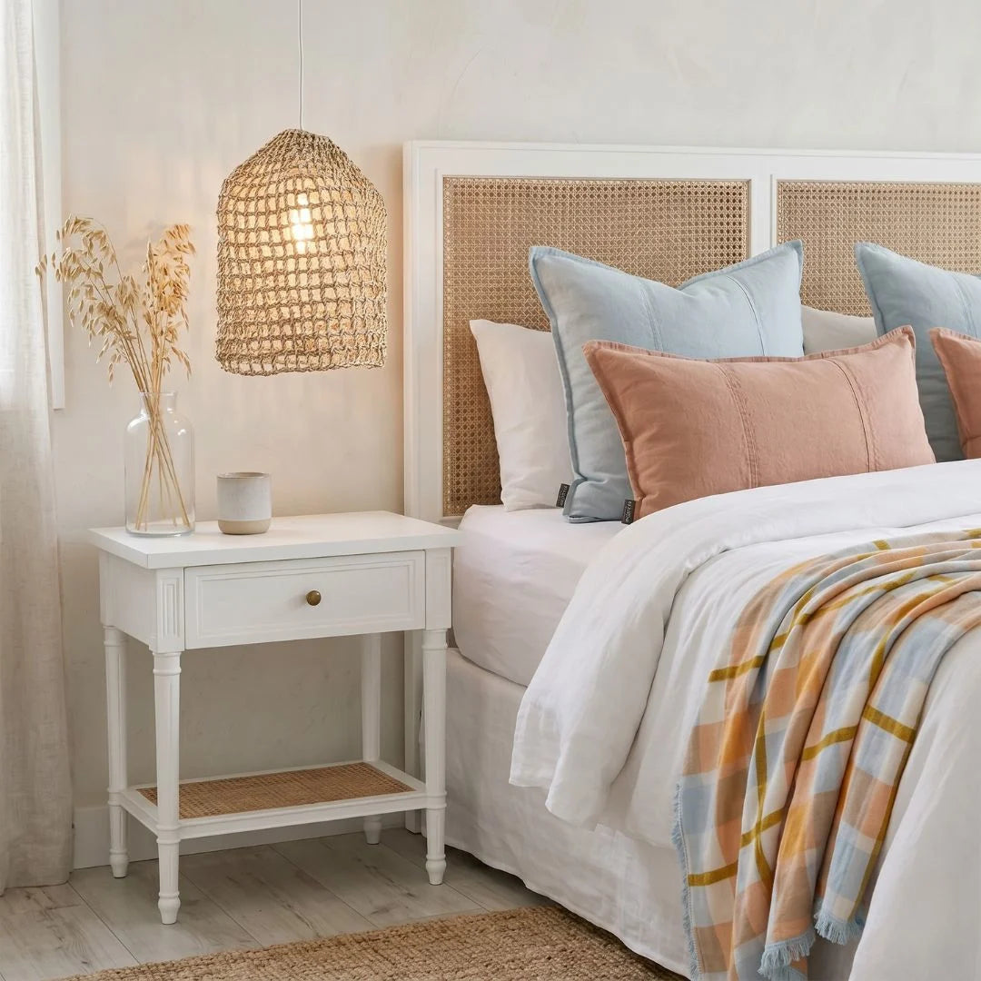 Bedroom with a bed featuring colorful pillows and a nightstand with decorative items.