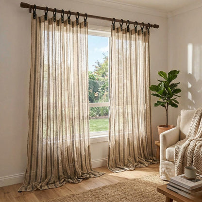 Sheer curtains with a subtle pattern in a living room setting with a plant and coffee table.