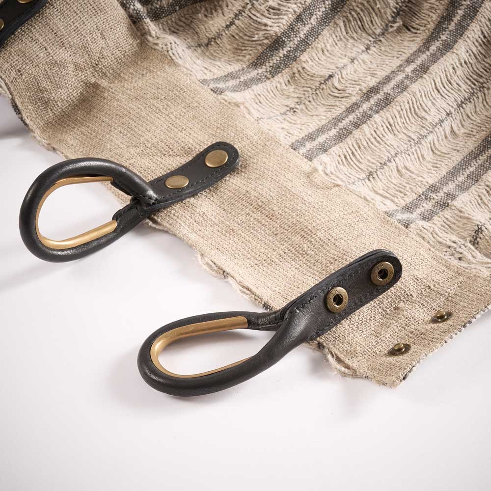Close-up of leather straps with metal hooks on a textured curtains