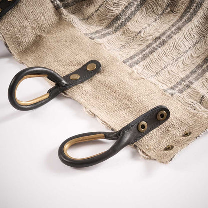 Close-up of leather straps with metal hooks on a textured curtains