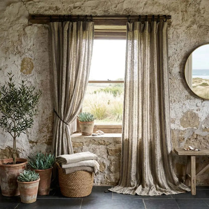 Room with stone walls, large windows with striped curtains, potted plants, and a woven basket.