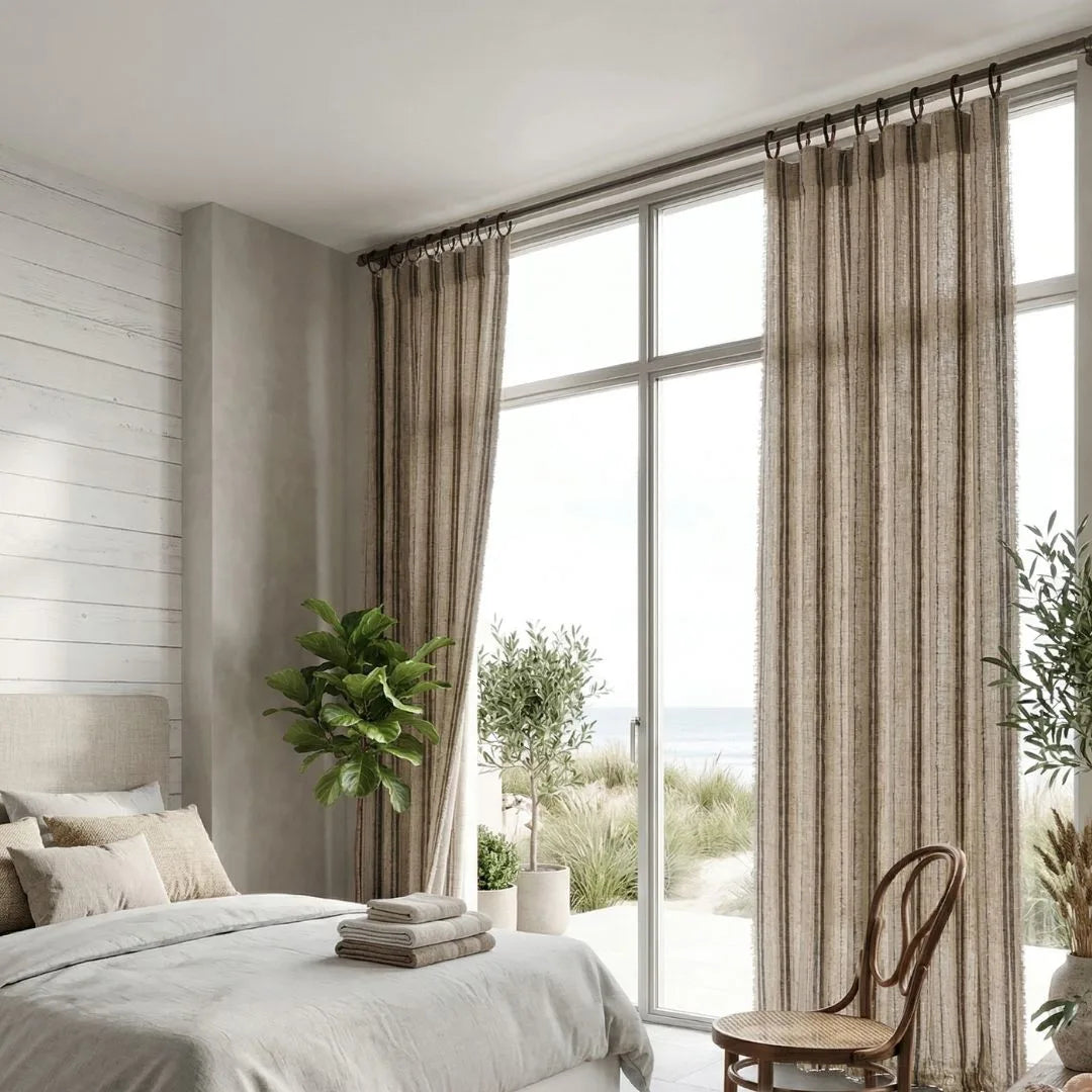 Modern bedroom with large windows, striped curtains, and decorative plants.