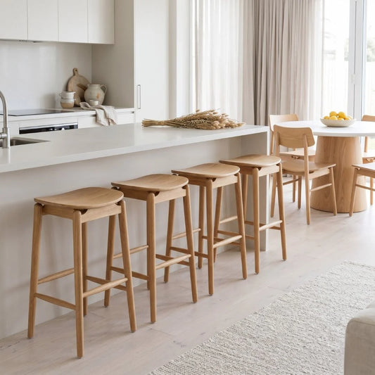 Wooden bar stools in a modern kitchen setting with white countertops and neutral decor.