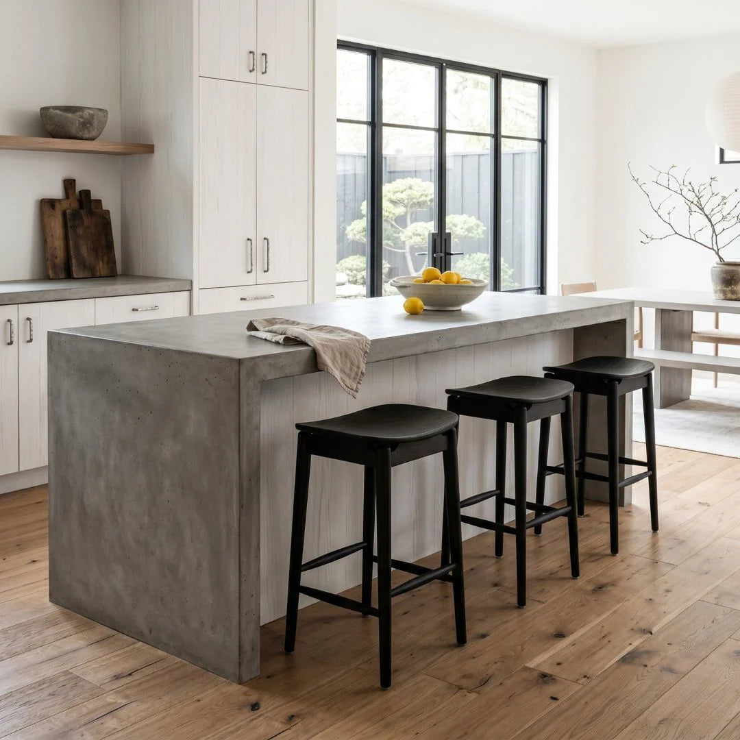 Modern kitchen with concrete island and black bar stools