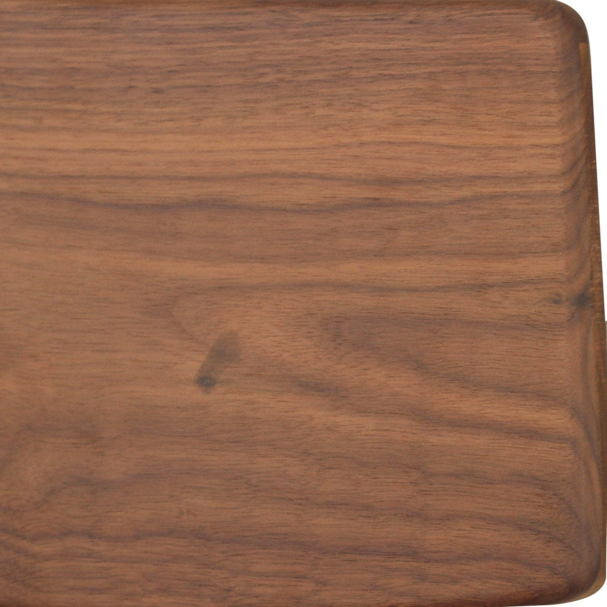A close-up of a walnut jansen stool, showing a warm medium-brown wood grain texture.