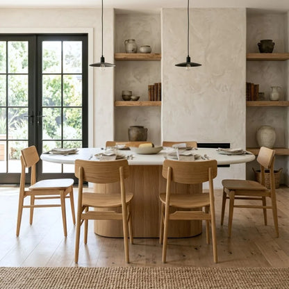 Dining area with wooden chairs and a round table in a well-lit room.