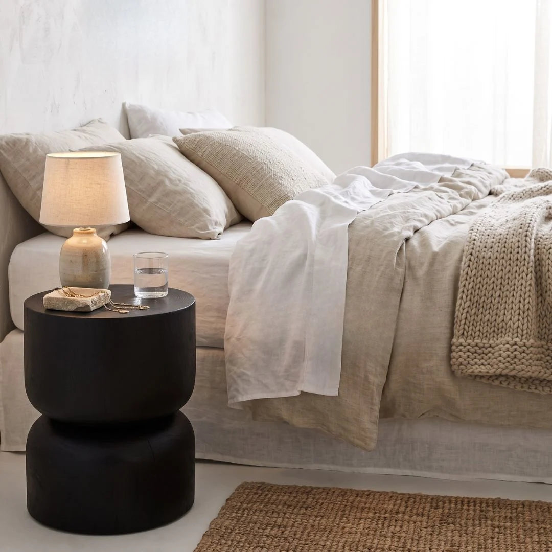 Modern living room with a bed, and black stump side table.