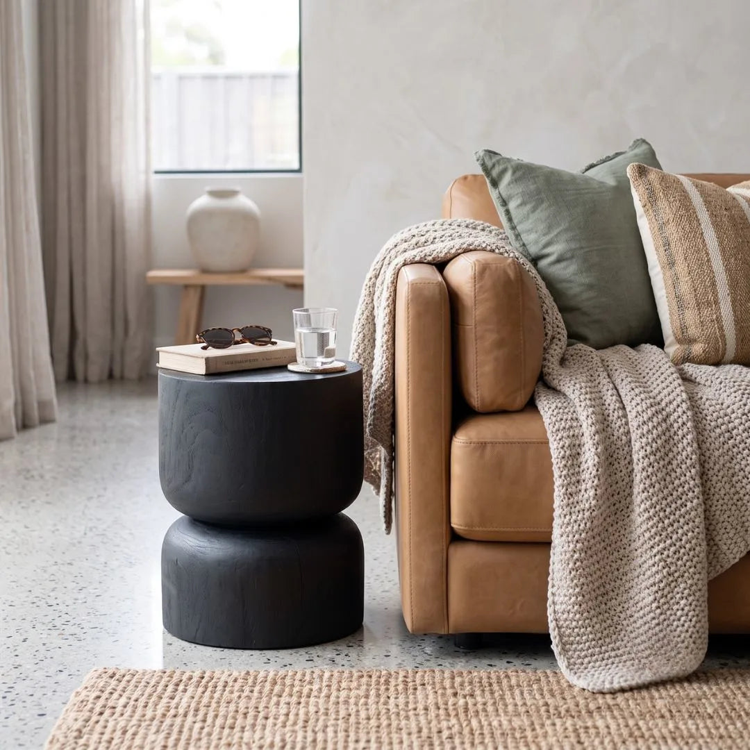 Modern living room with a sofa, and black stump side table.