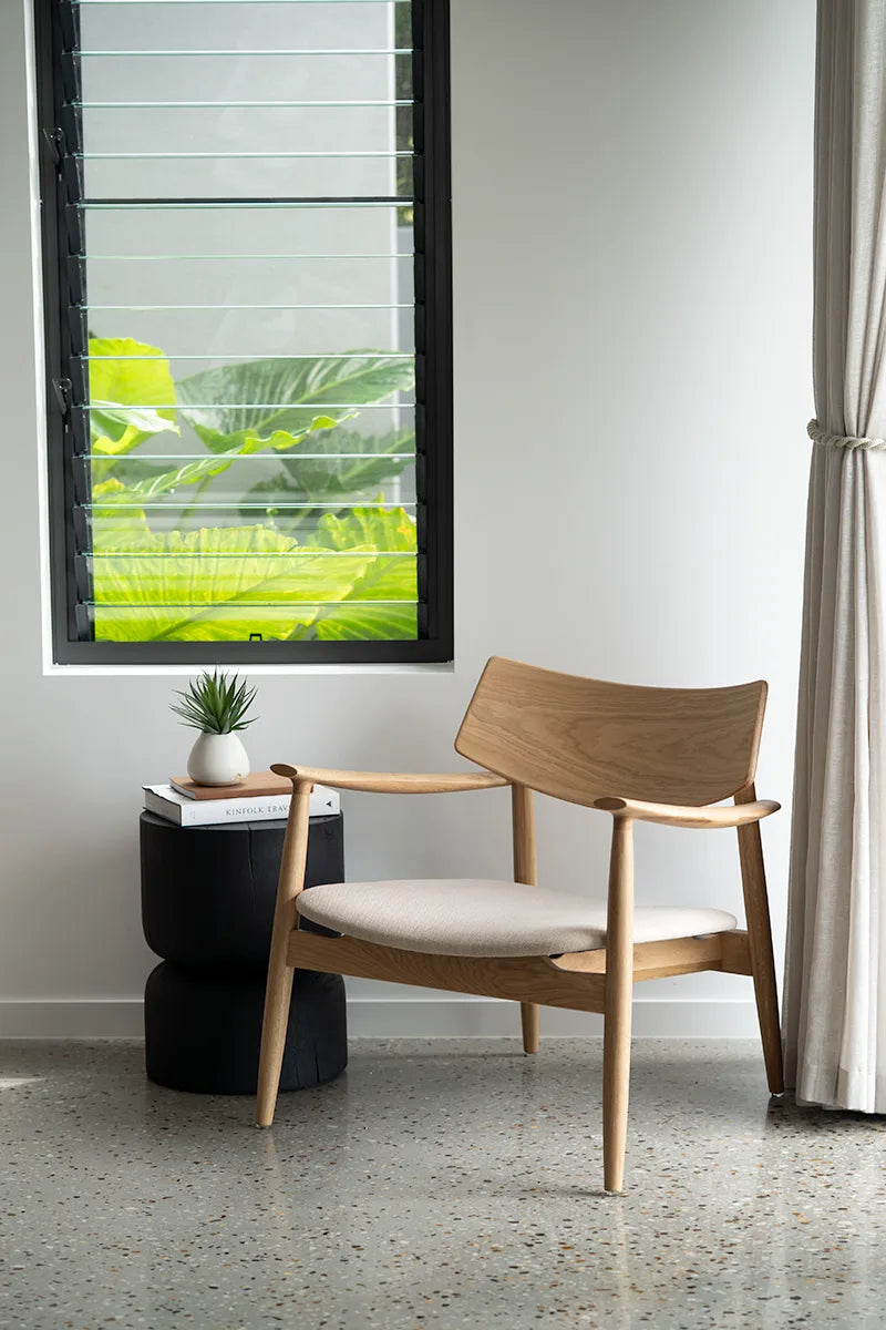 Wooden chair with white cushion in a room with a window and plant