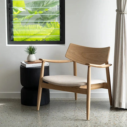 Wooden chair with white cushion in a room with a window and plant