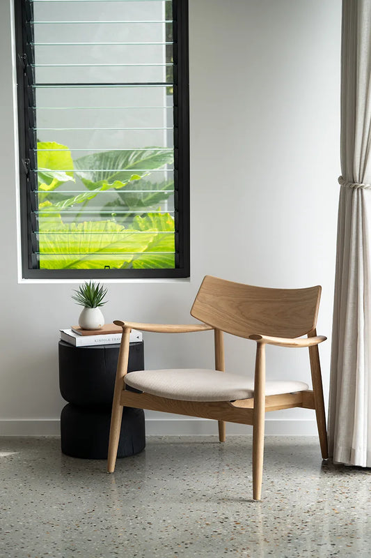Wooden chair with white cushion in a room with a window and plant