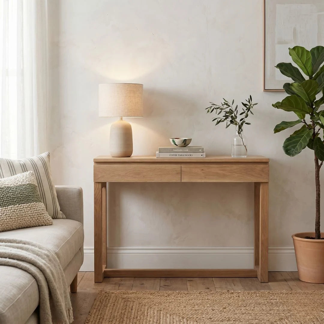 Wooden console table in a living room setting with a lamp, books, and plant.