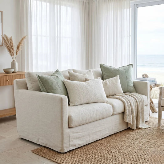 Beige sofa with decorative pillows and a blanket in a bright living room.