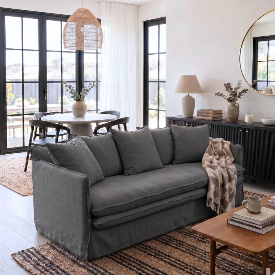 Living room with a gray sofa, wooden coffee table, and round mirror.