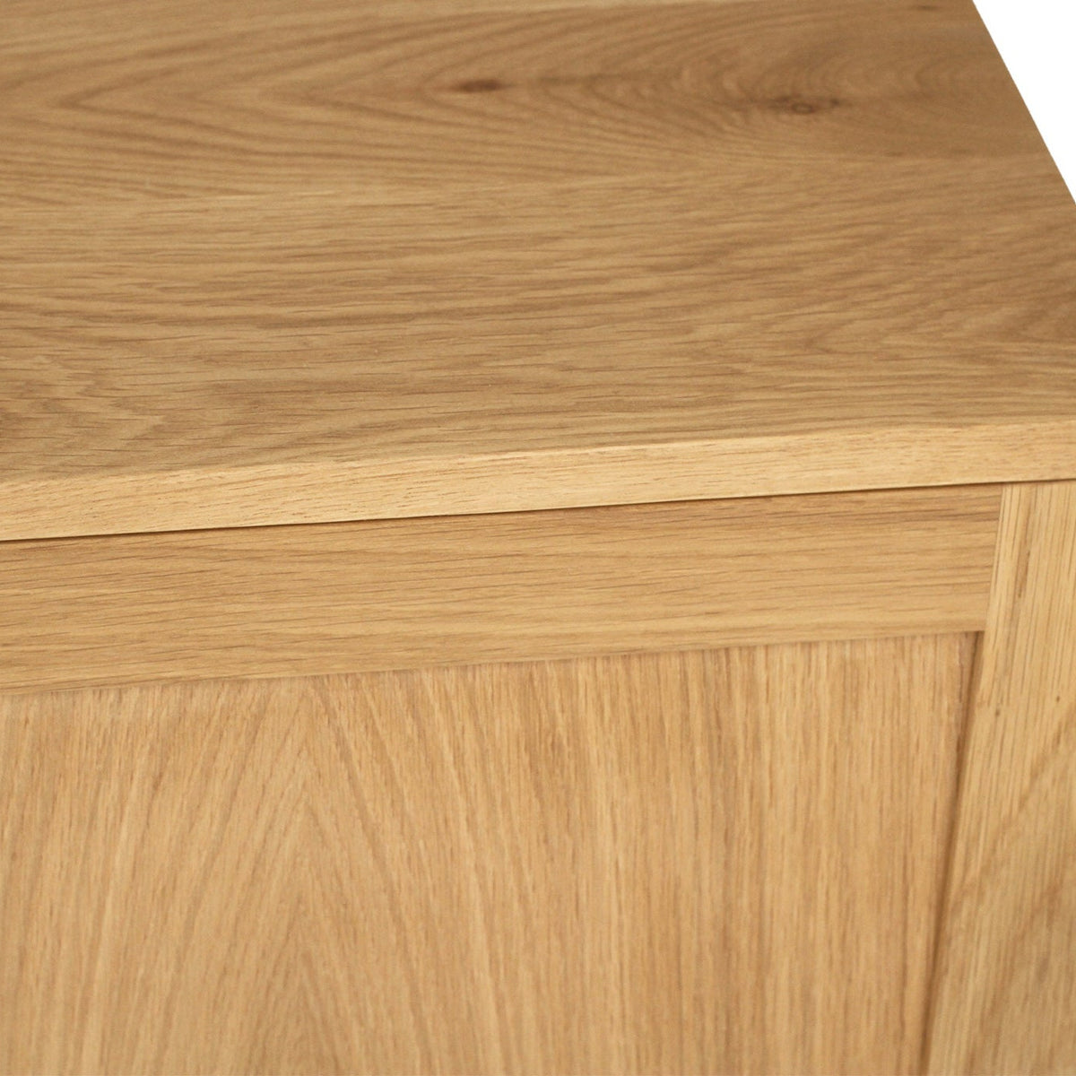 Close-up of a light oak wood cabinet or sideboard showing the top surface, front panel, and clean white background.