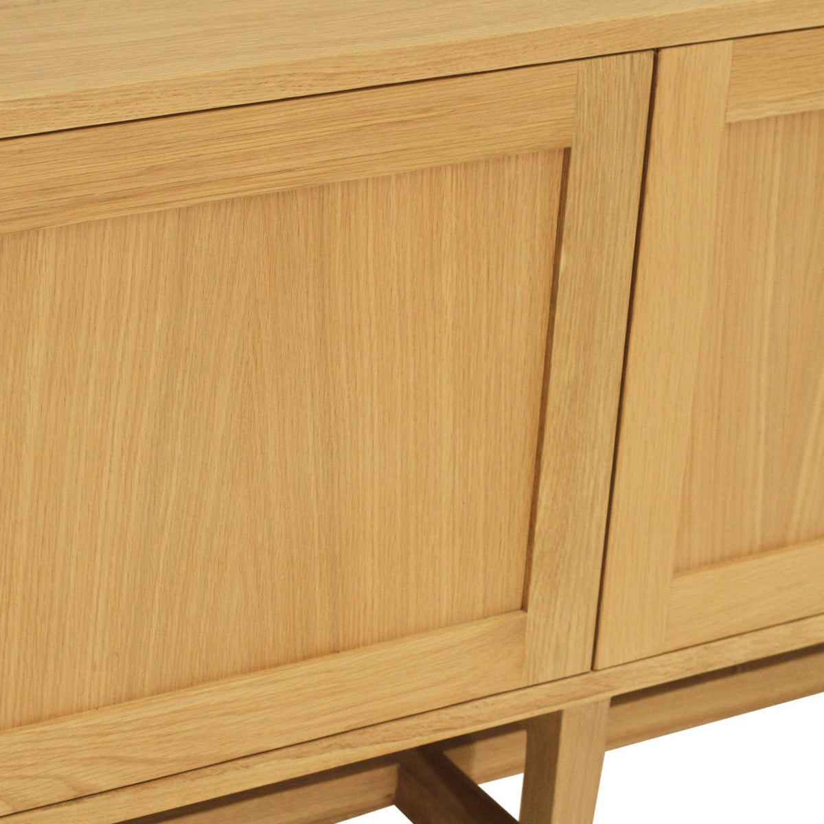 Close-up of a light oak wood sideboard or cabinet with paneled doors and visible wood grain texture.