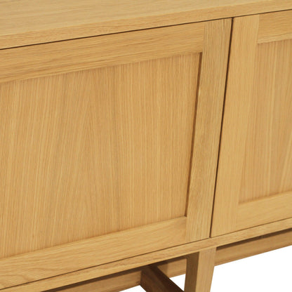 Close-up of a light oak wood sideboard or cabinet with paneled doors and visible wood grain texture.