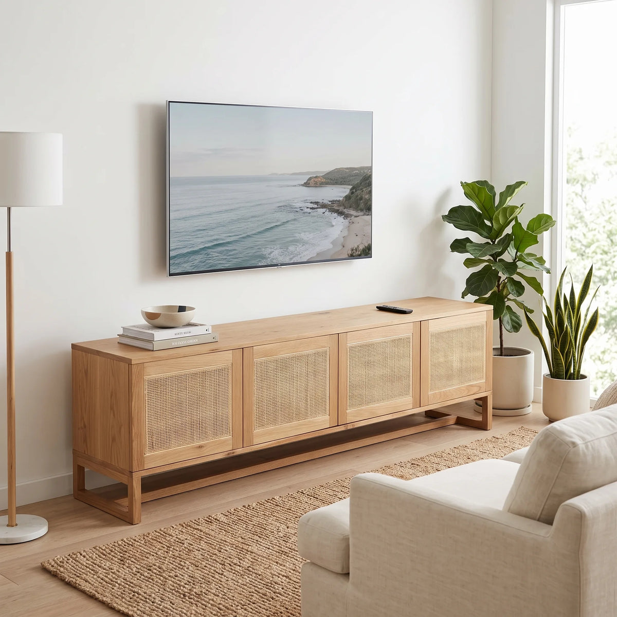 A light natural wood TV stand with woven cane doors, styled in a bright living room under a wall-mounted TV.