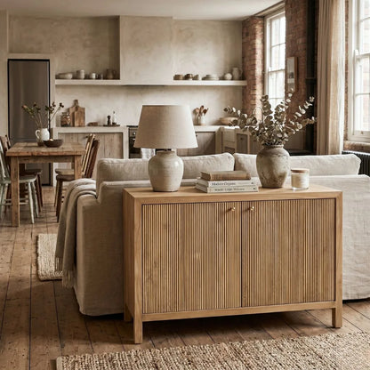 Living room with wooden sideboard, sofa, and kitchen in the background