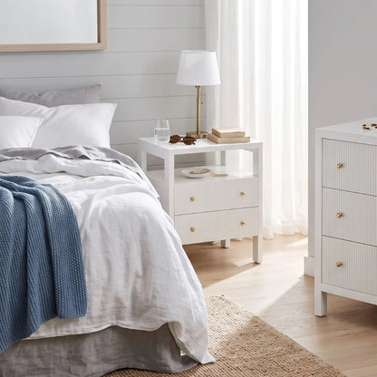Modern white bedside table and dresser in a coastal bedroom setting