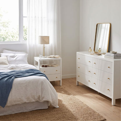 Modern white bedside table and dresser in a coastal bedroom setting
