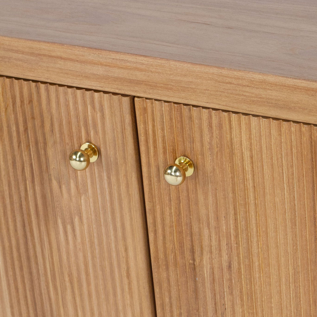 Close-up of a wooden cabinet with two doors, featuring vertical grain texture and round brass knobs.