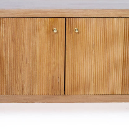 Close-up of a wooden sideboard cabinet with two doors featuring vertical fluting and small round brass handles, shown against a plain white background.