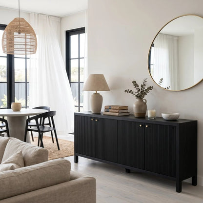Modern living room with black sideboard, round mirror, and neutral decor.