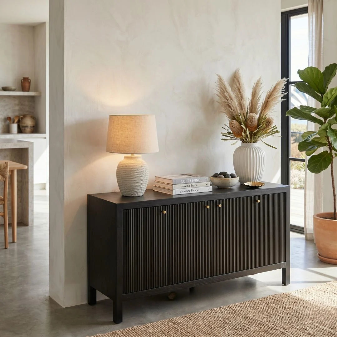 Dark wooden sideboard with lamp, books, and decorative items in a living room setting.