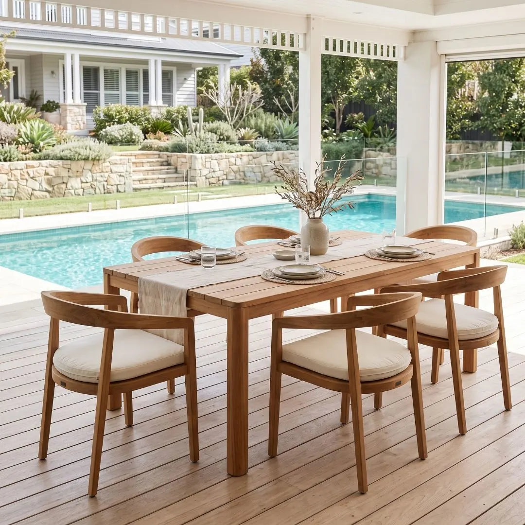Wooden dining table with chairs on a wooden deck by a pool