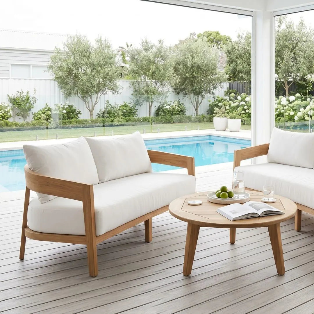 Outdoor patio set with wooden frames and white cushions by a pool.