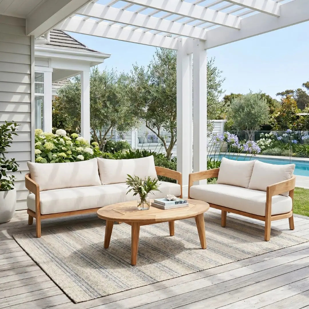 Outdoor patio set with white cushions on a wooden deck, featuring a sofa and two chairs with a coffee table.