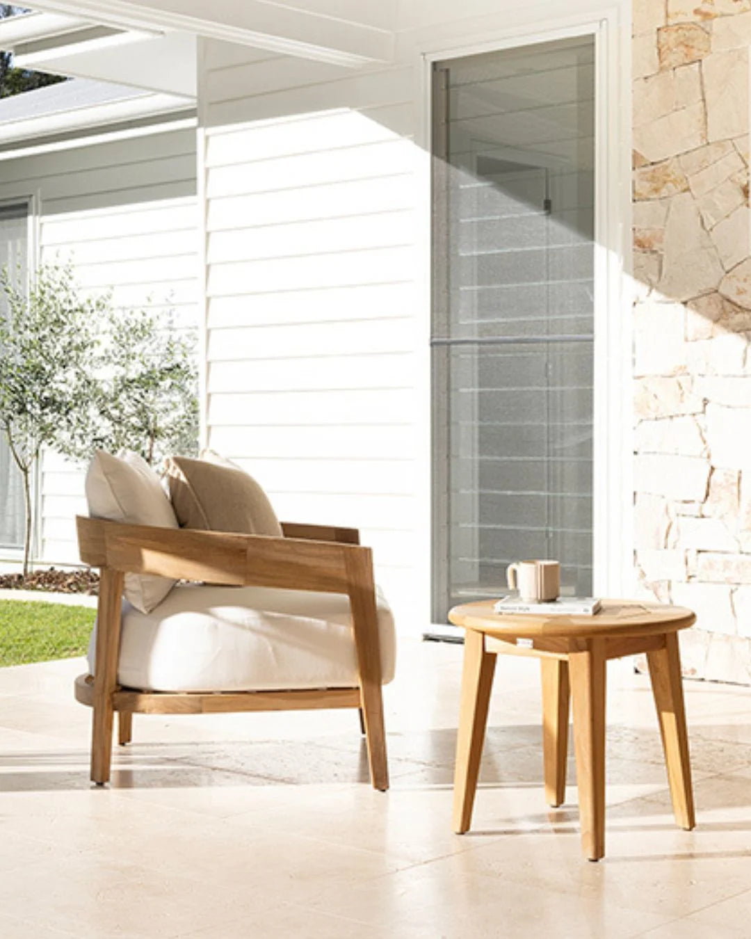 Teak outdoor chair and Roud Teak side table on a patio with a neutral background
