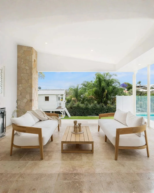 Modern outdoor living space with white sofas, wooden coffee table, and scenic view.
