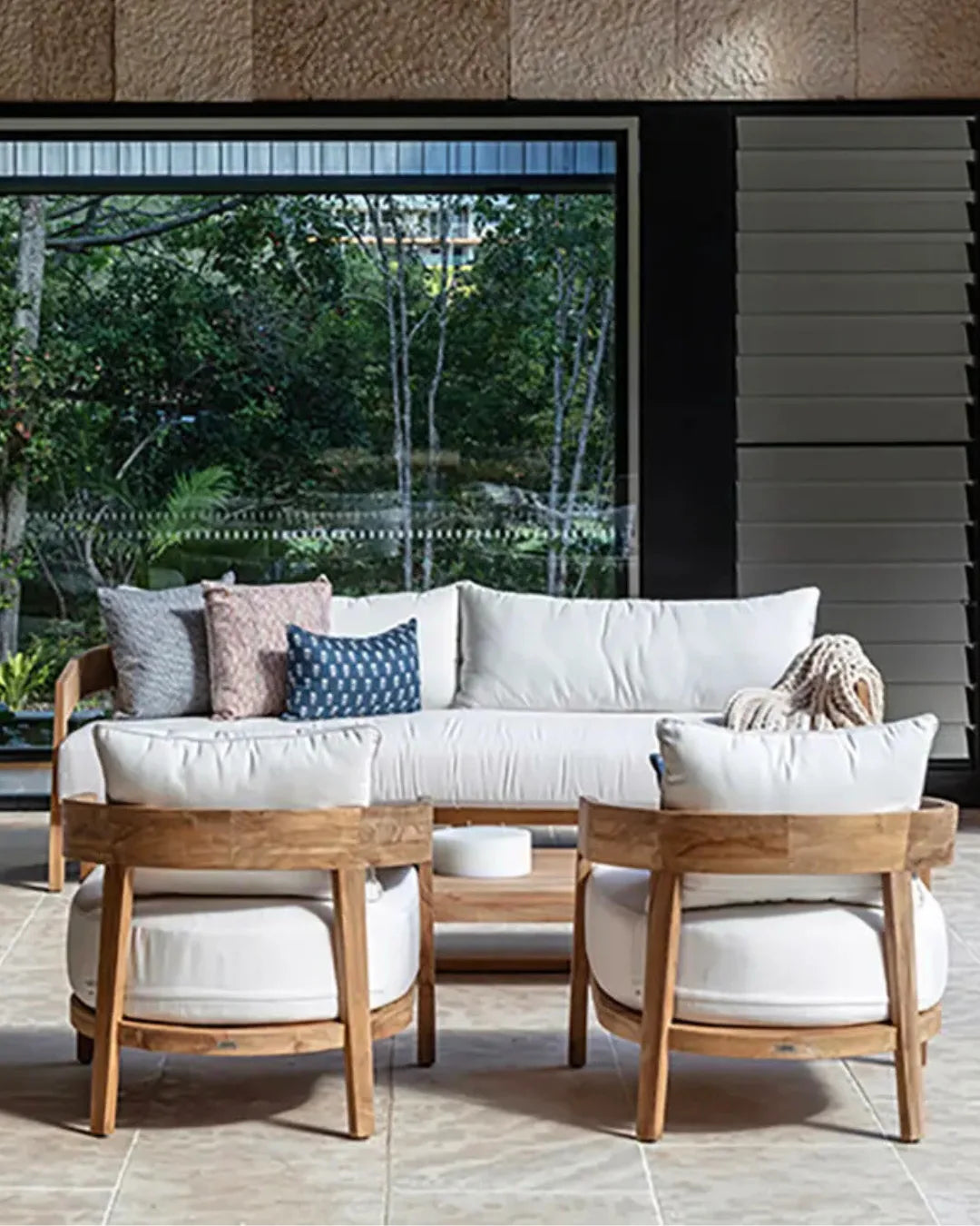 Outdoor furniture set with white cushions and wooden frames in a modern patio setting.