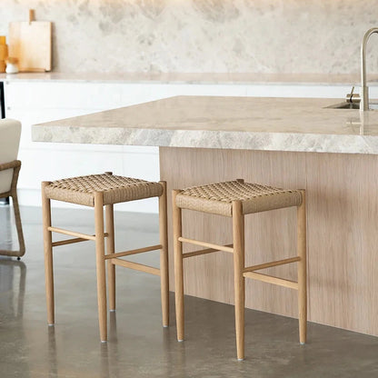 Two wooden stools with woven seats in a modern kitchen setting.