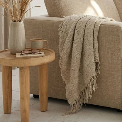 Cozy living room scene with a beige sofa, wooden side table, and decorative items.