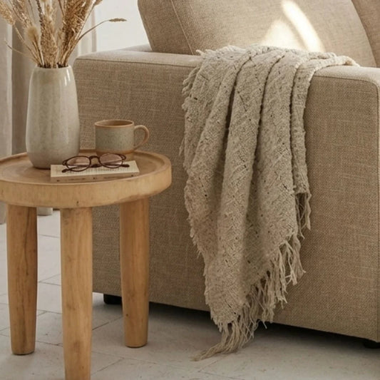 Cozy living room scene with a beige sofa, wooden side table, and decorative items.