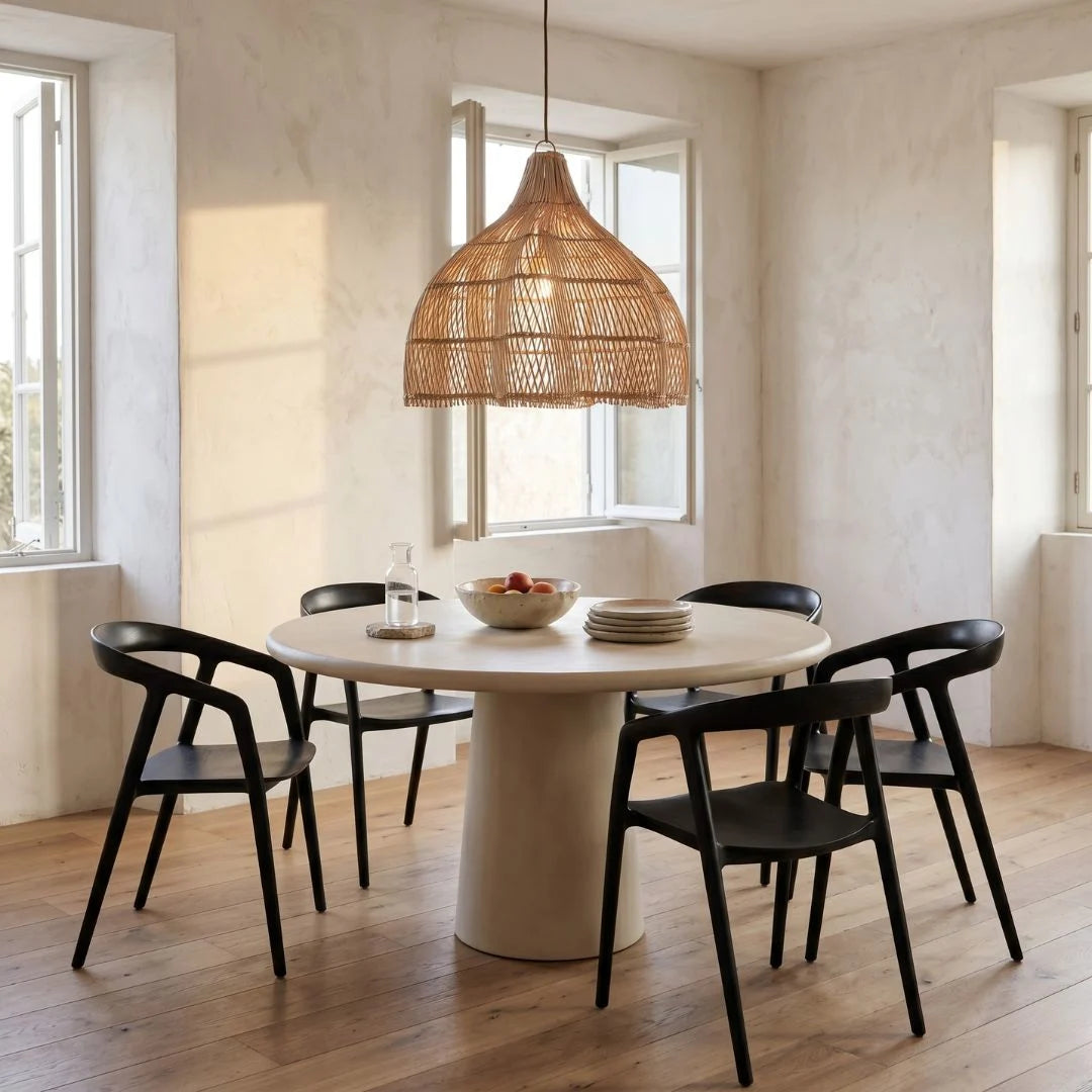 Dining area with a round table and black chairs under a large rattan pendant light.