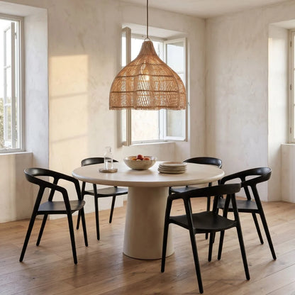 Dining area with a round table and black chairs under a large rattan pendant light.
