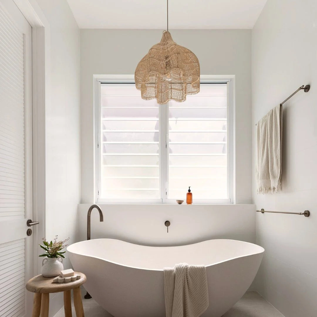 Modern bathroom with a freestanding bathtub,lotus rattan pendant light, and window with white blinds.