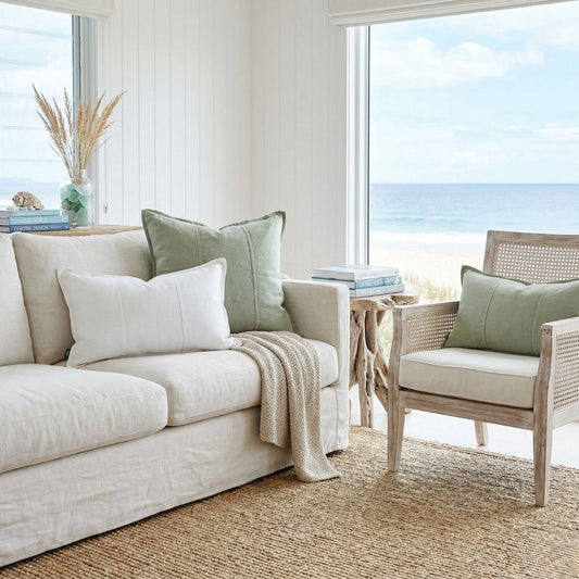 Living room with beige sofa, wicker chair, and ocean view
